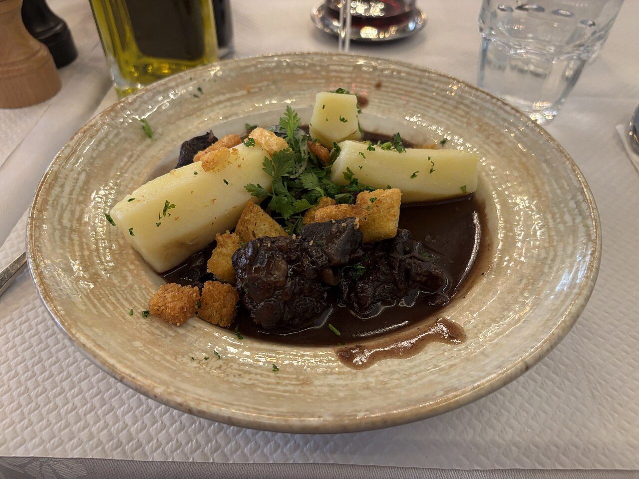 Prato de boeuf bourguignon com batatas cozidas e croutons, servido num restaurante em Paris
