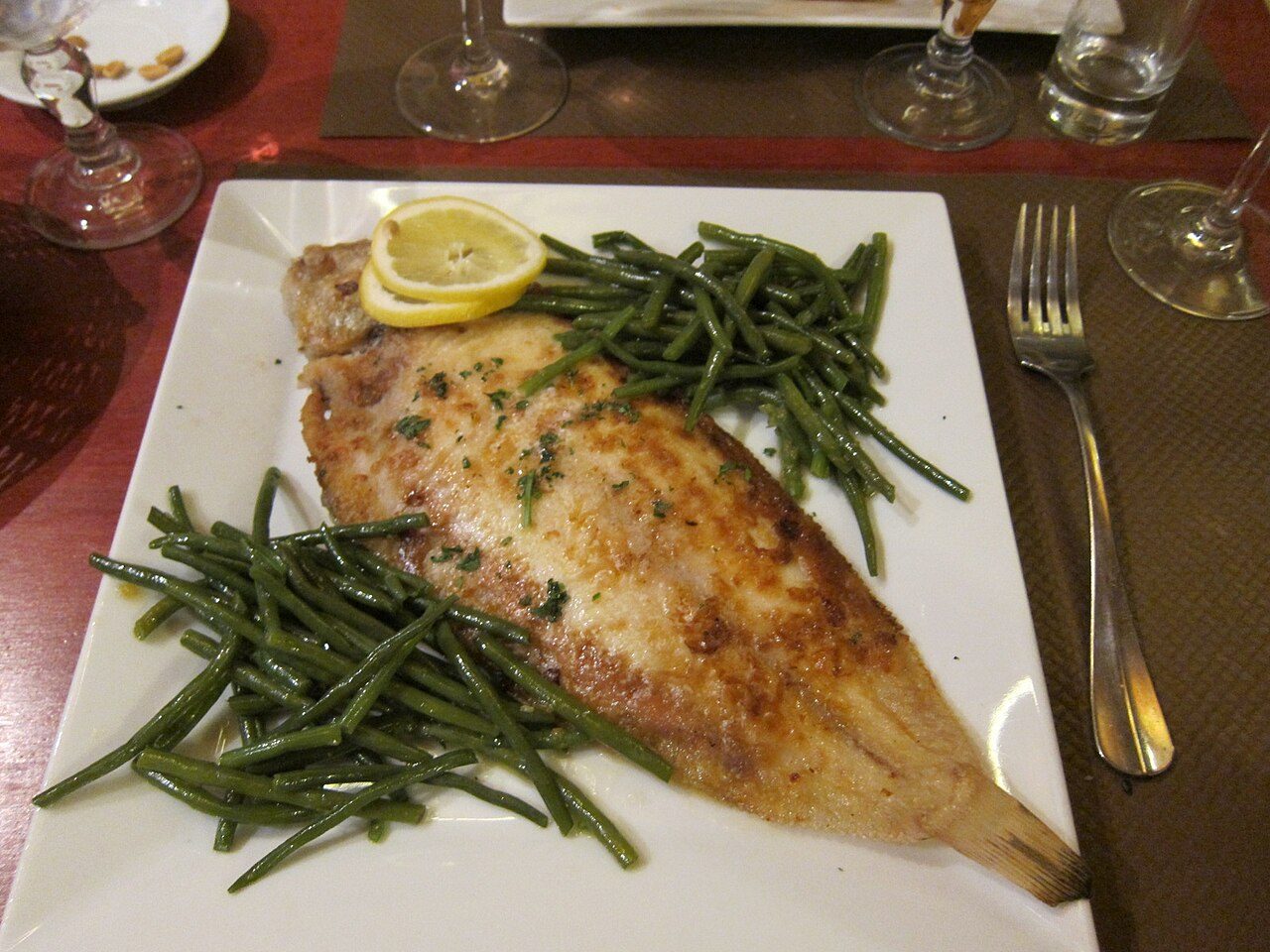 Linguado inteiro dourado à meunière com rodelas de limão e vagem fina no prato