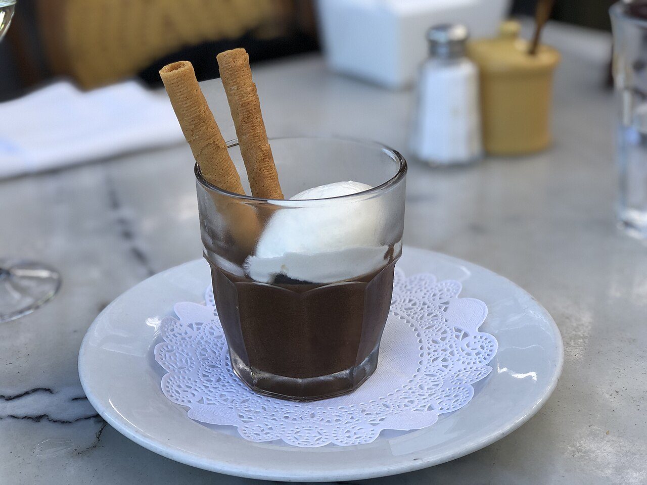 Mousse de chocolate servida em copo com chantilly e biscoitos em um bistrô francês